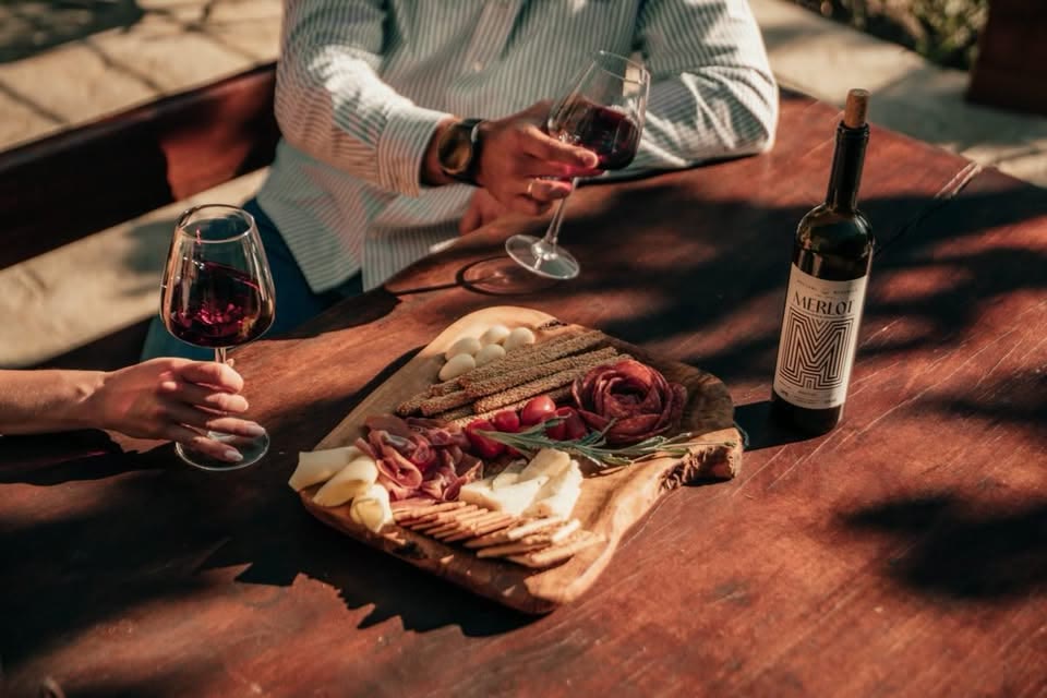 Ζευγάρι απολαμβάνει κρητικό κρασί και μεζέδες σε ξύλινο τραπέζι